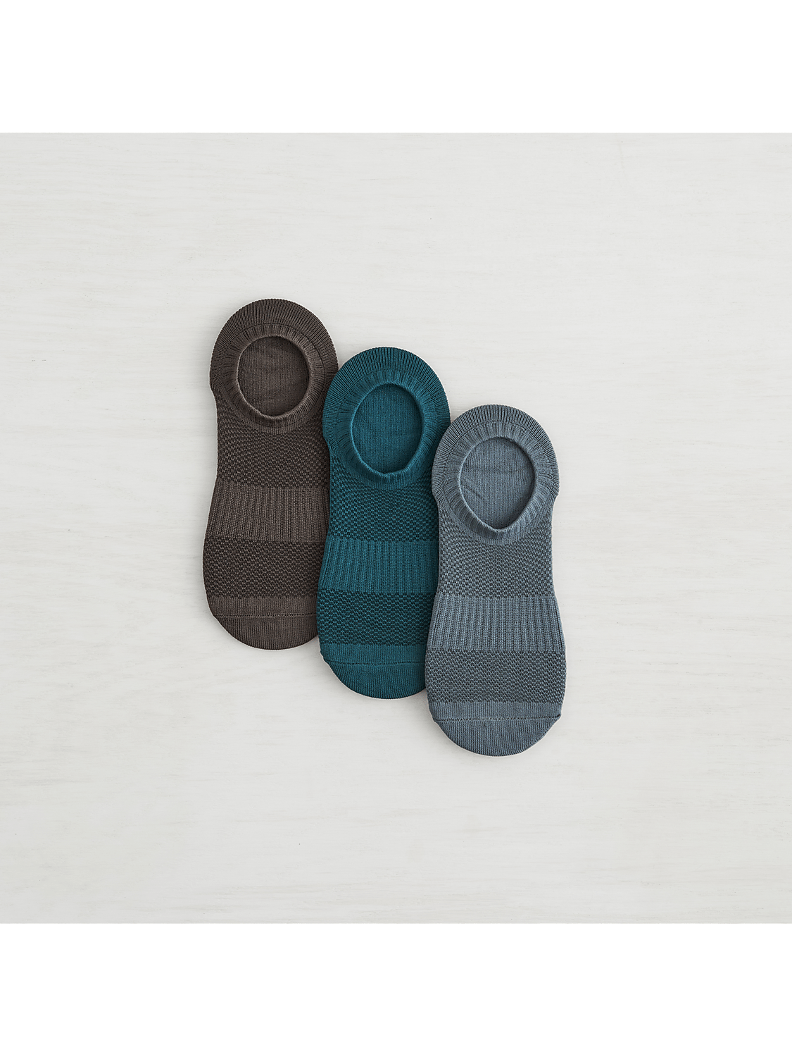 Three no-show socks in brown, teal, and gray are arranged on a white, textured surface. Product Image 5