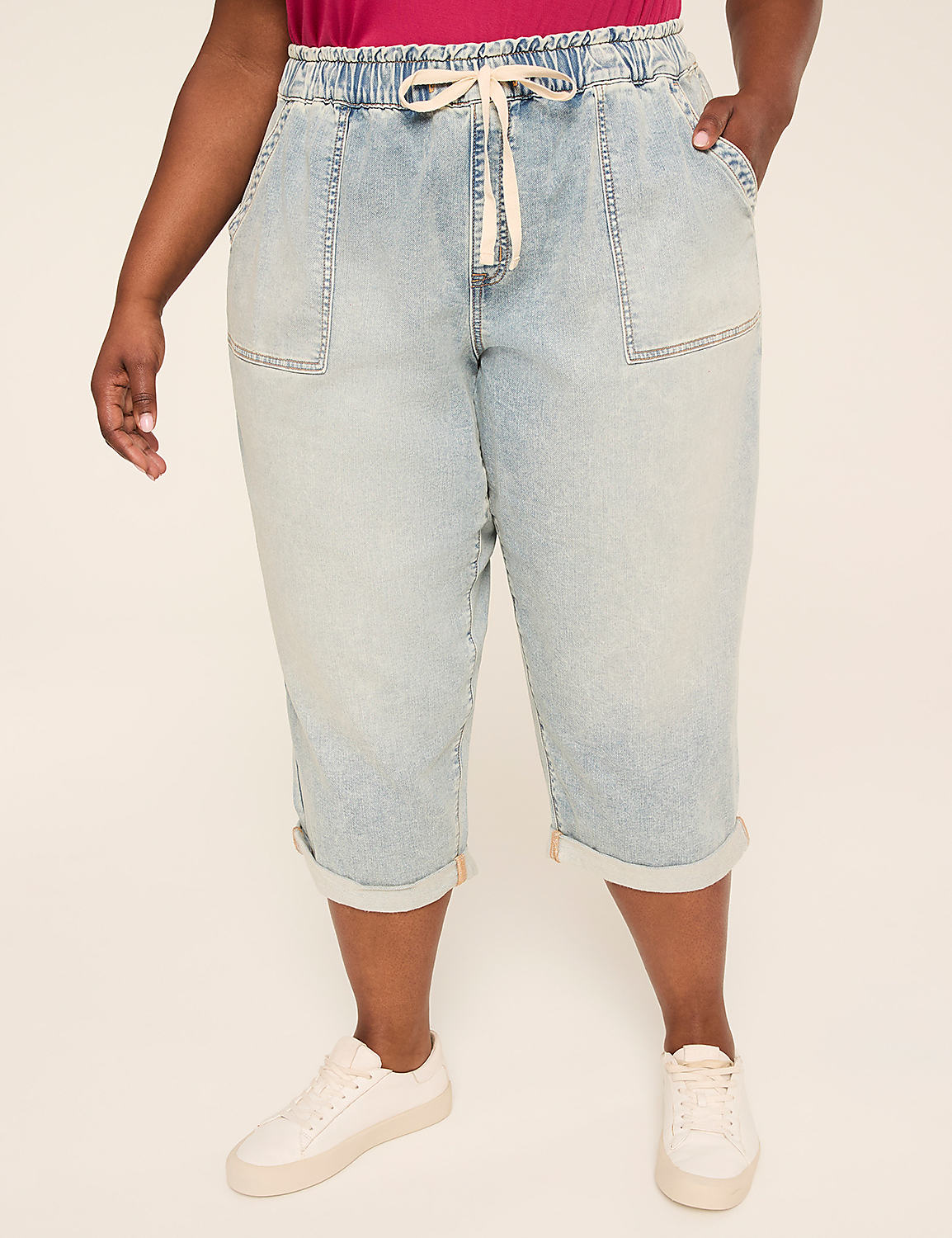 A person stands in light-wash denim capri pants with cuffed hems and a cream drawstring, against a plain, light-colored background. Product Image 1