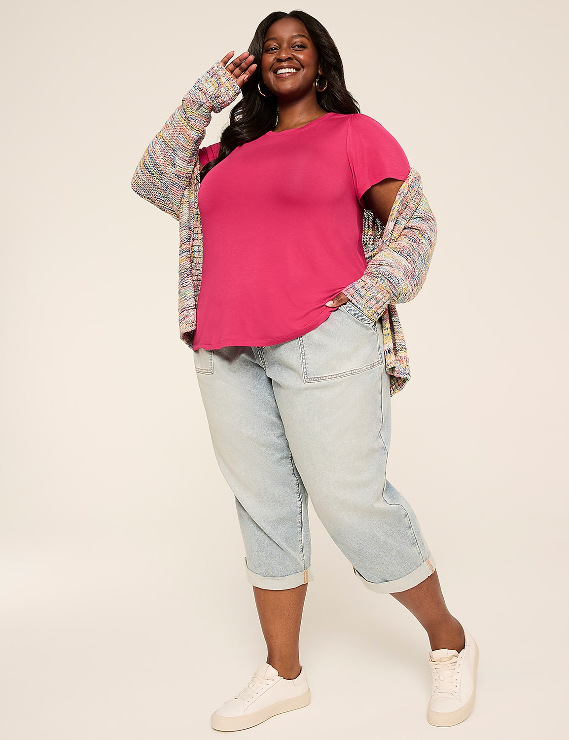 A smiling woman in a pink t-shirt, colorful cardigan, and light-wash capri jeans stands against a plain, light-colored background. Product Image 3