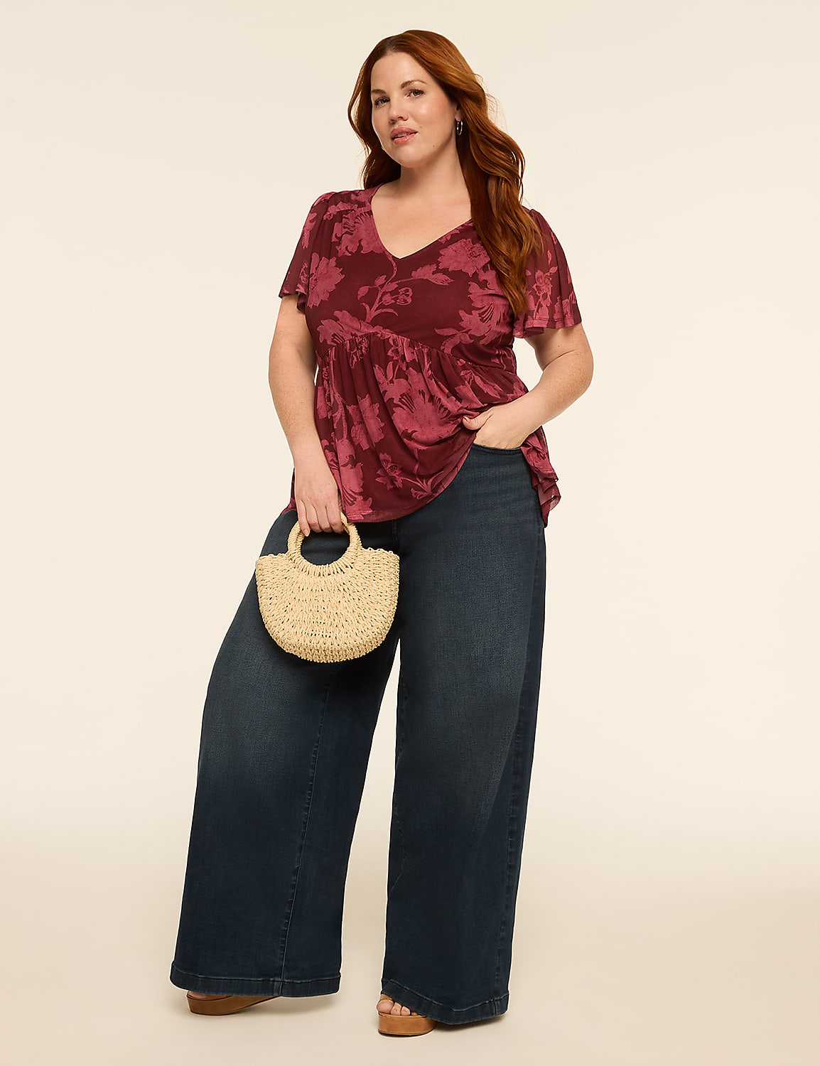 A smiling woman with red hair in a maroon t-shirt and wide-leg jeans stands against a plain, light-colored background. Product Image 3