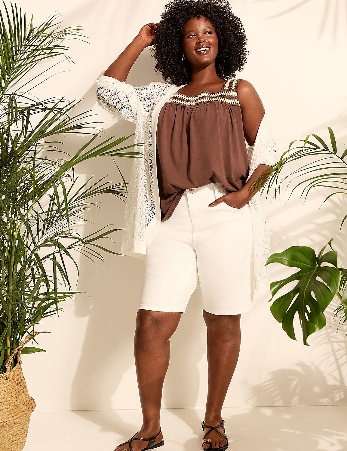 A woman in a brown top and white shorts stands among lush green plants with dappled sunlight in the background. Product Image 5