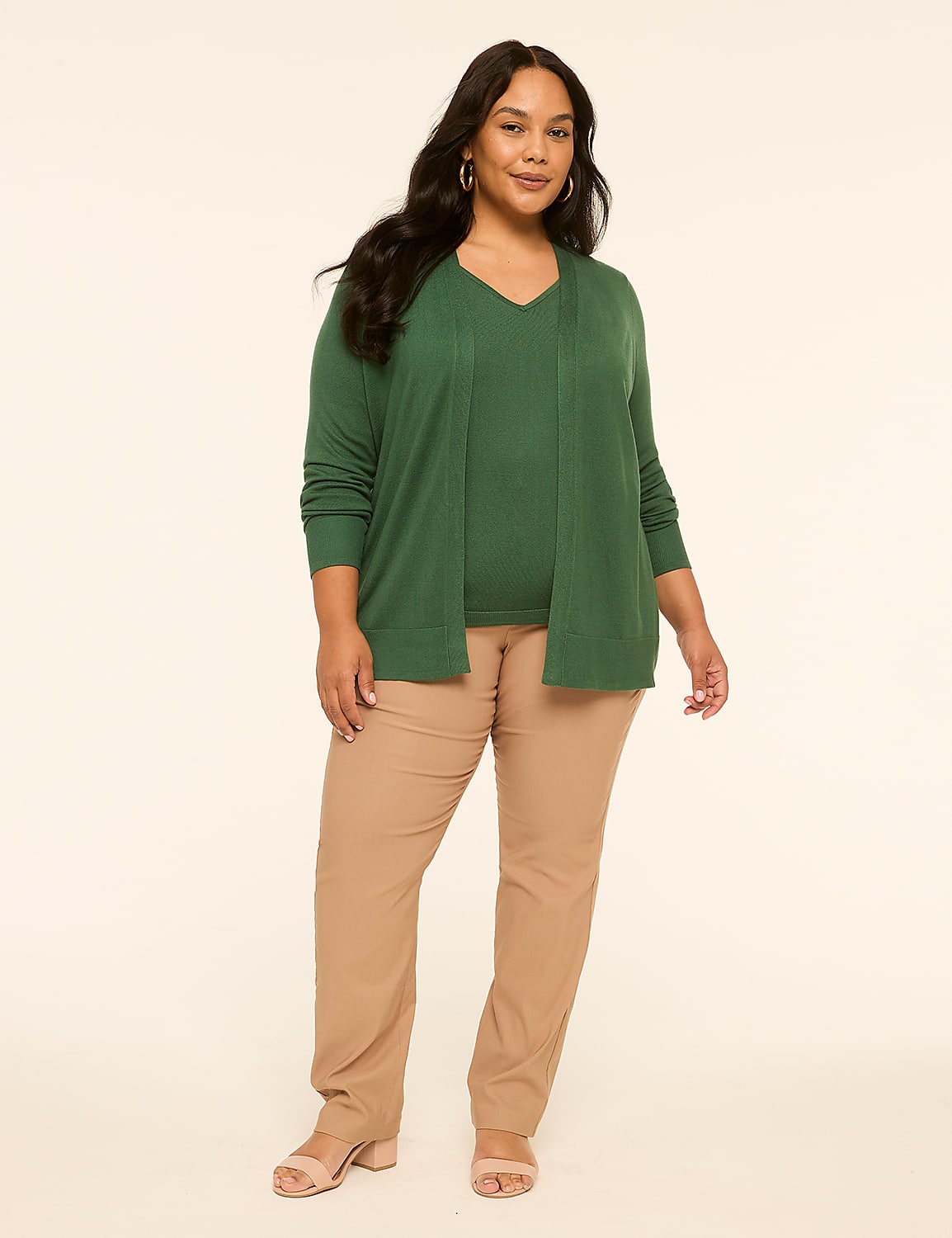 A woman in a green sweater and tan pants stands against a plain, light-colored background. Product Image 3