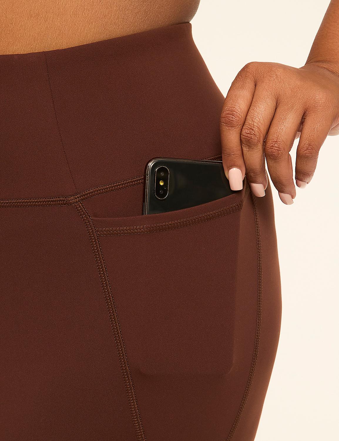 A hand with manicured nails places a smartphone into the pocket of brown leggings against a plain background. Product Image 4