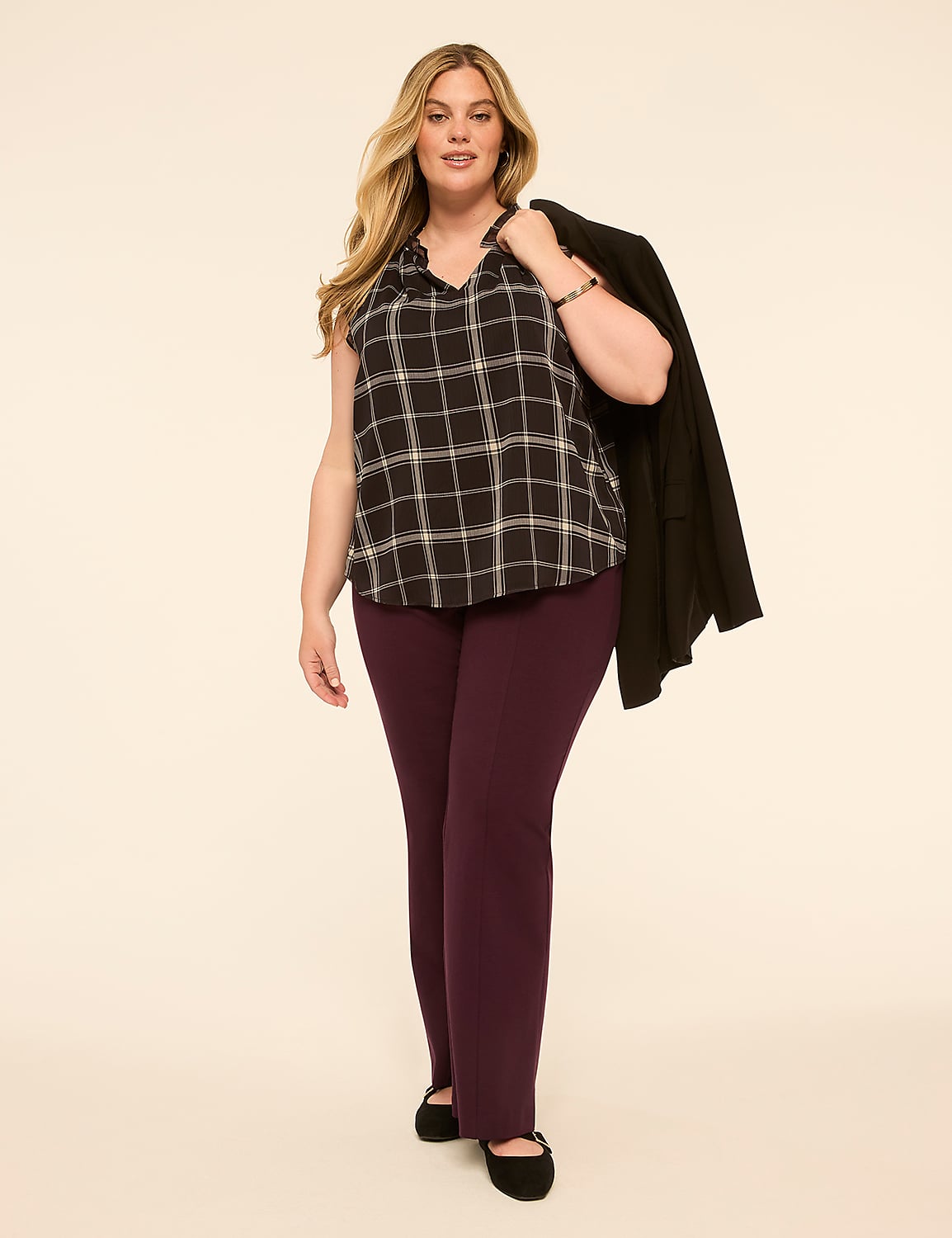 A woman in a plaid top and plum pants stands against a plain, light-colored background with a black blazer draped over her shoulder. Product Image 3