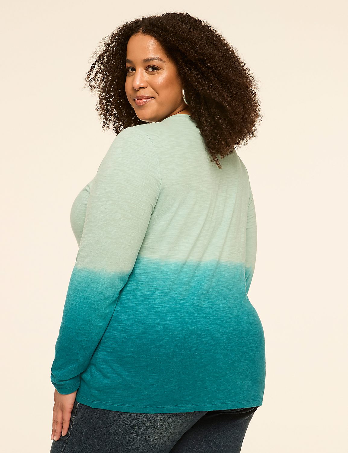 A woman with curly hair poses in a teal and mint green ombre shirt against a plain cream background. Product Image 2