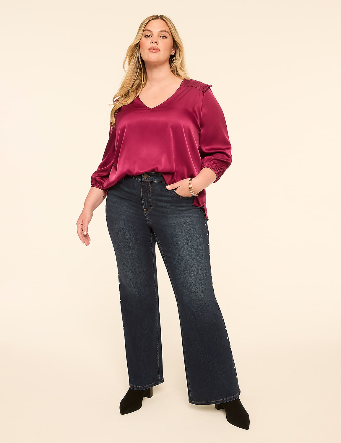 A woman in a satin top and flared jeans stands against a plain, light-colored background. Product Image 3