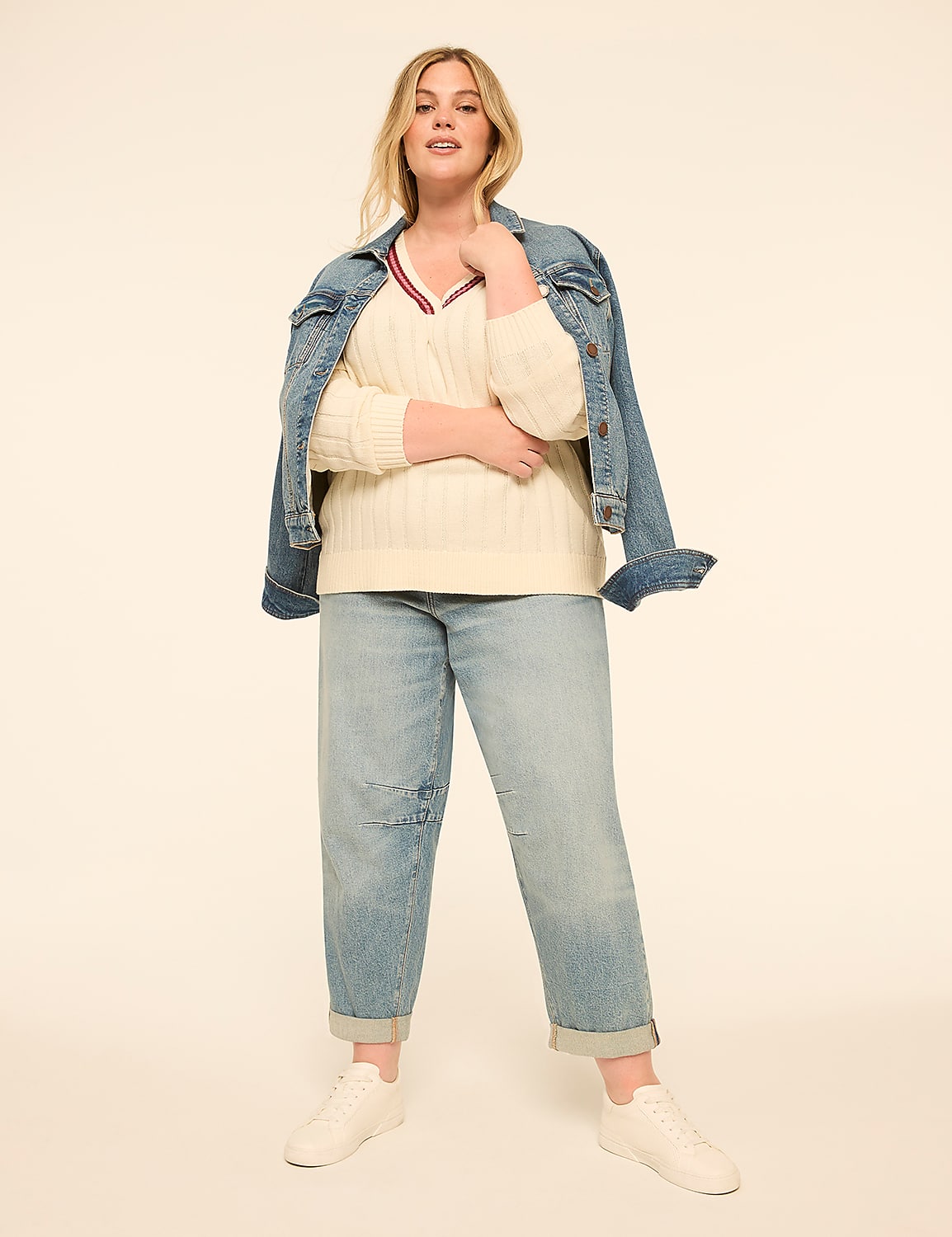 A woman in a cream cable-knit sweater, denim jacket, and light-wash jeans stands against a plain, light-colored background. Product Image 3