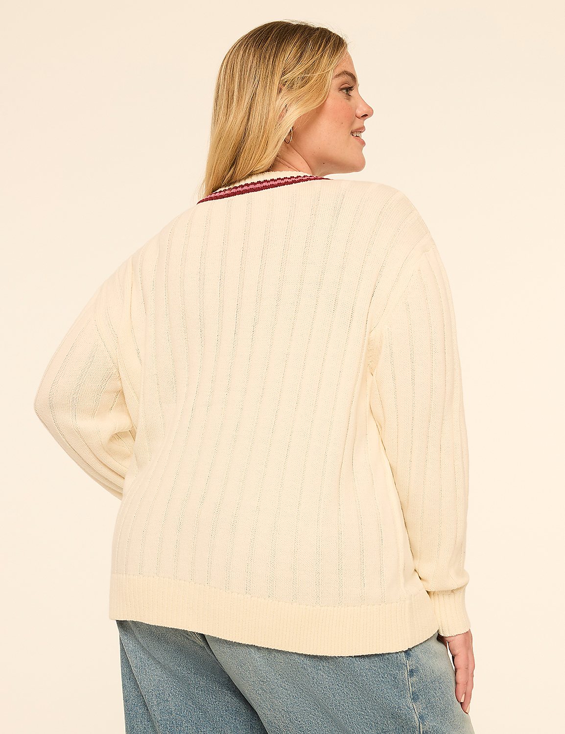 A woman in a cream cable-knit sweater and blue jeans stands against a plain, light-colored background. Product Image 2