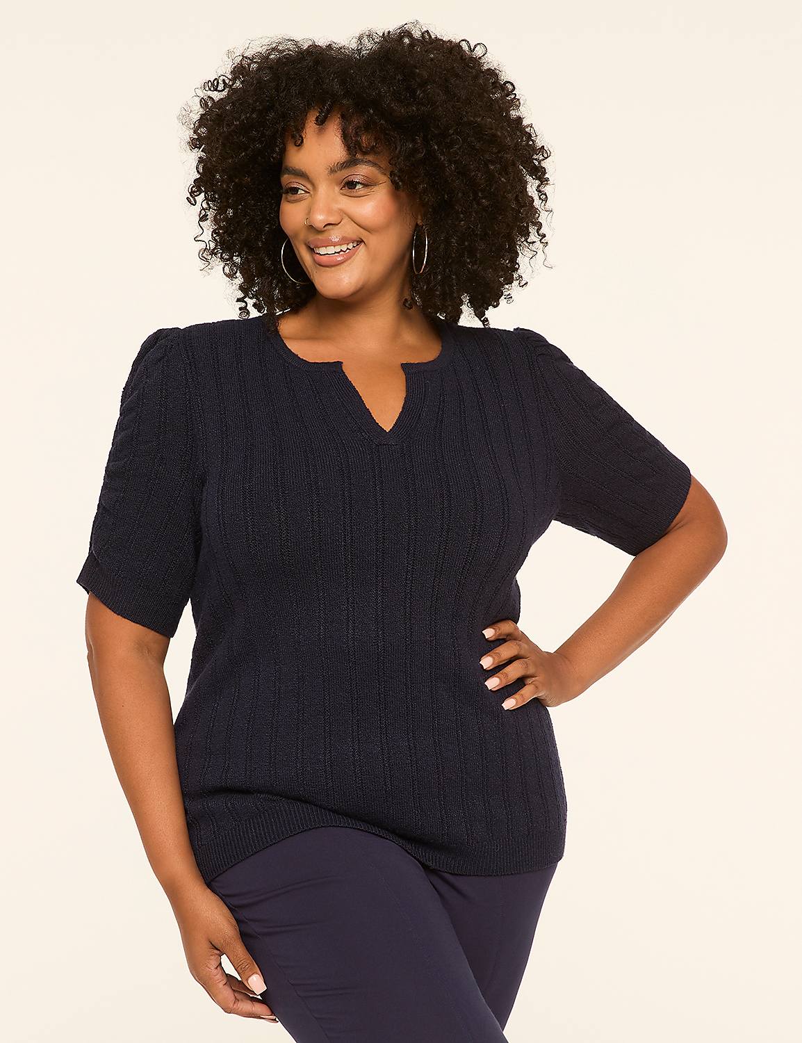 A smiling woman with curly hair poses in a navy blue sweater and pants against a plain, light-colored background. Product Image 1