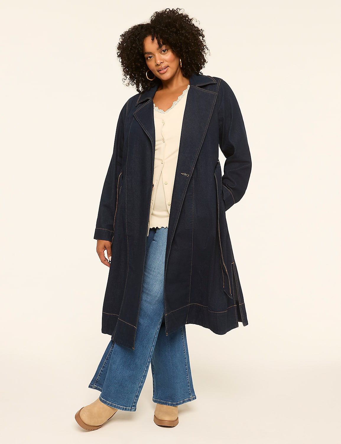 A woman in a denim trench coat and flared jeans stands against a plain, light-colored background. Product Image 3