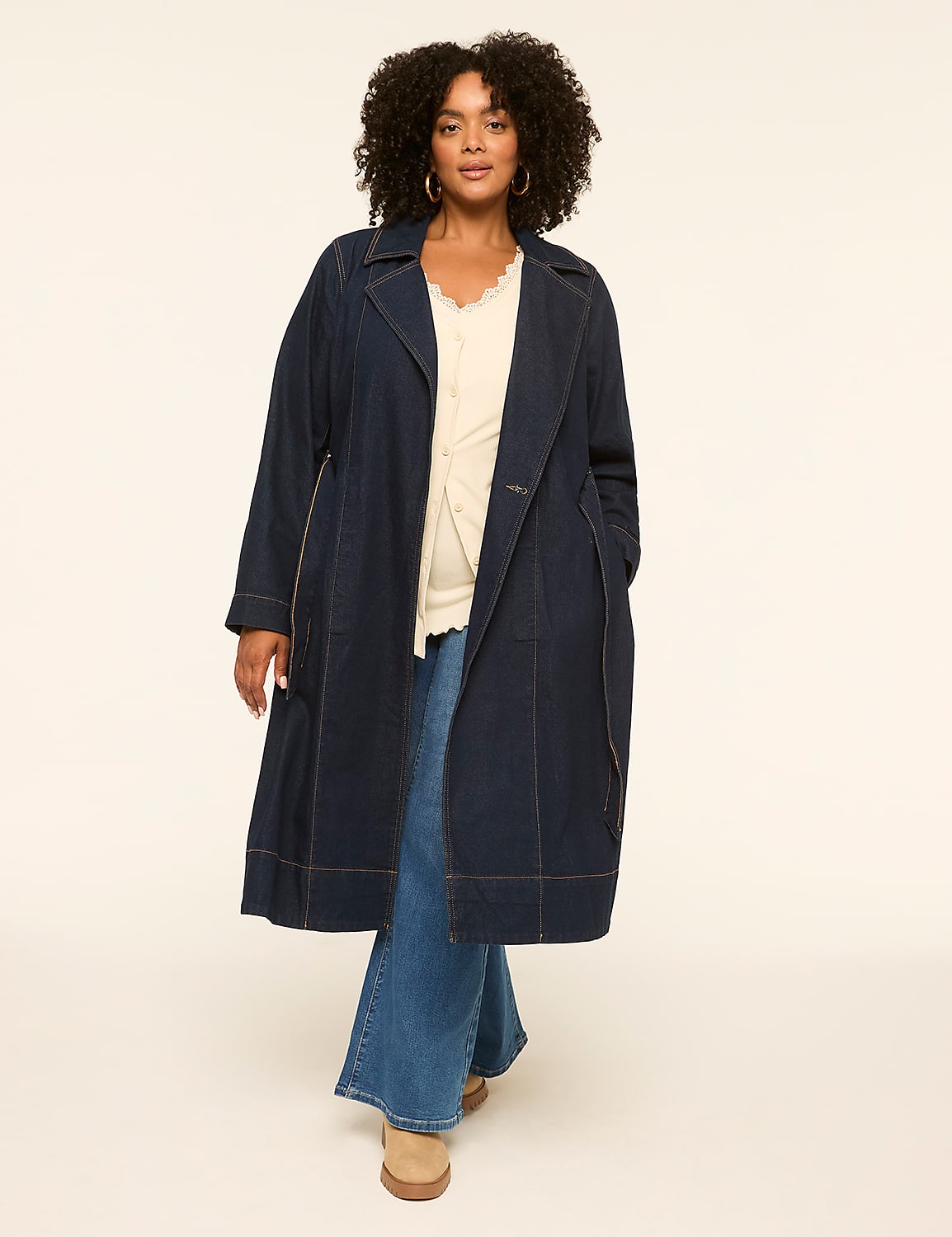 A woman with curly dark hair stands in a denim trench coat and wide-leg jeans against a plain, light-colored background. Product Image 3