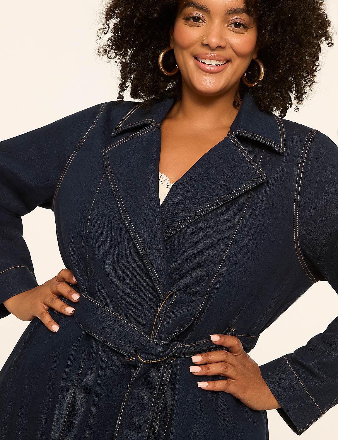 A smiling woman in a denim trench coat with her hands on her hips stands against a plain, light-colored background. Product Image 4