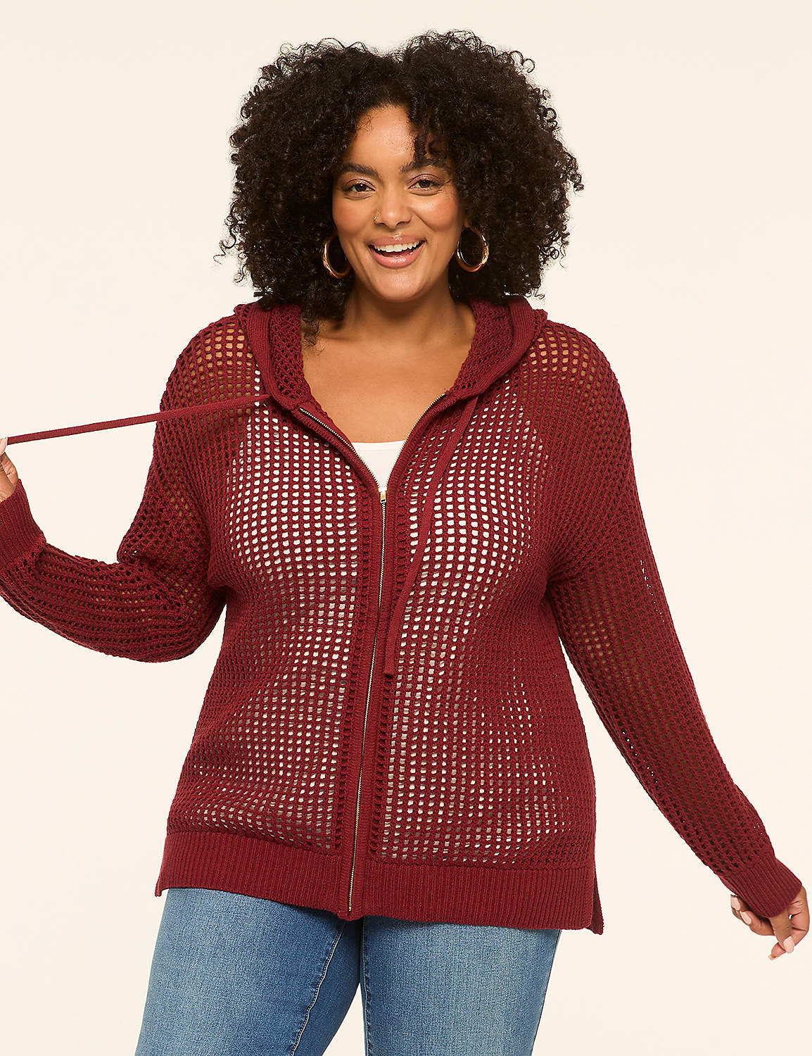 A smiling woman in a maroon open-knit zip-up hoodie stands against a plain cream background. Product Image 1