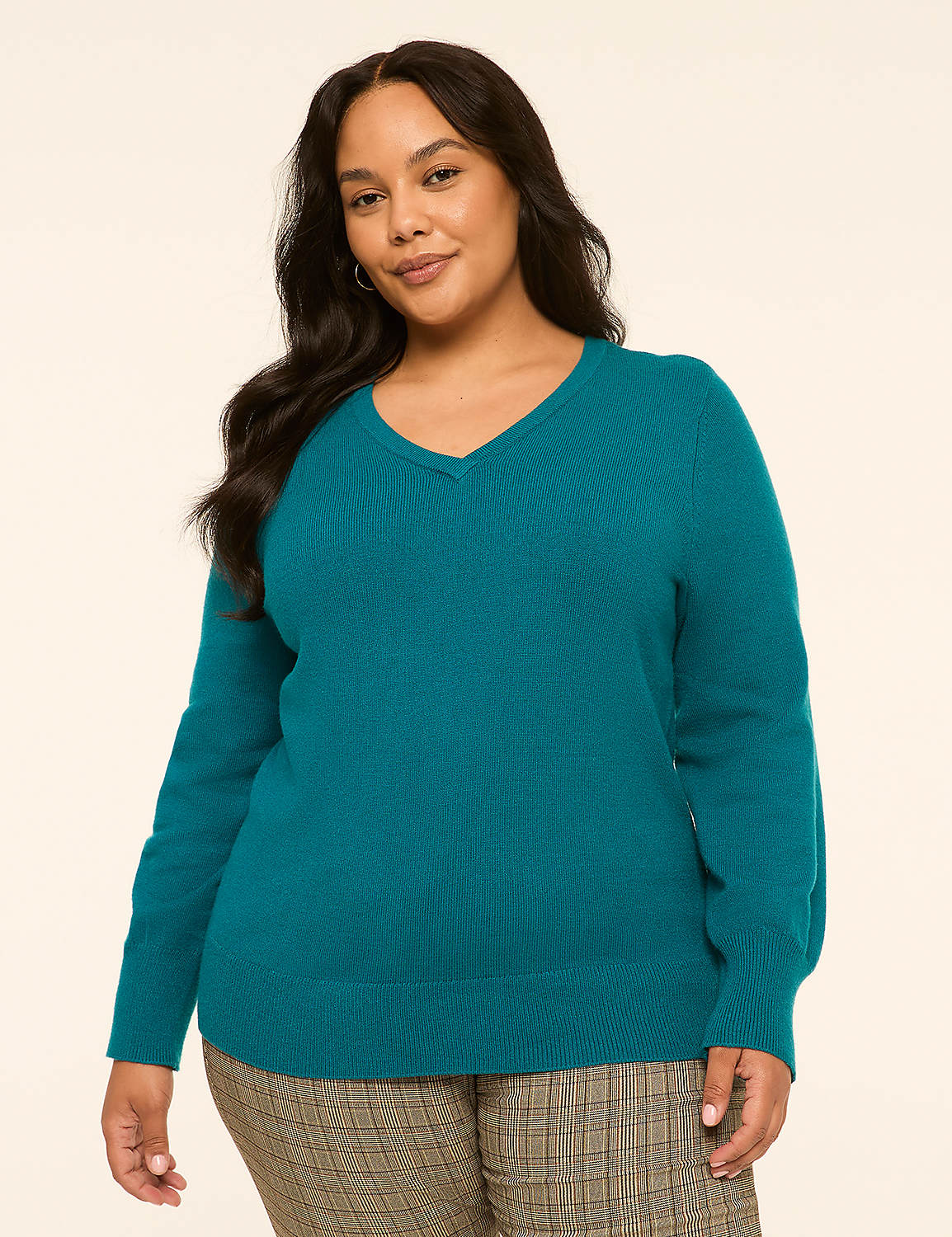 A woman in a teal v-neck sweater and plaid pants stands against a plain, light-colored background. Product Image 1