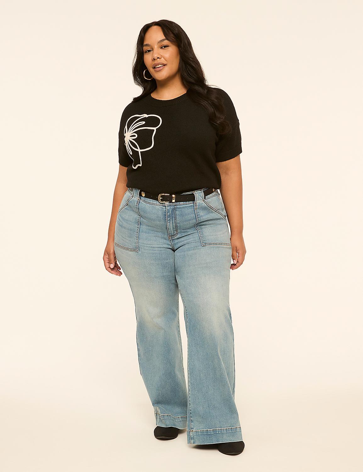 A woman in a black t-shirt with a white graphic and light-wash wide-leg jeans stands against a plain, light-colored background. Product Image 3