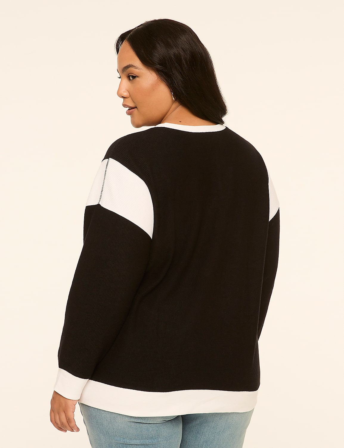 A woman in a black and white sweatshirt stands against a plain, light-colored background. Product Image 2