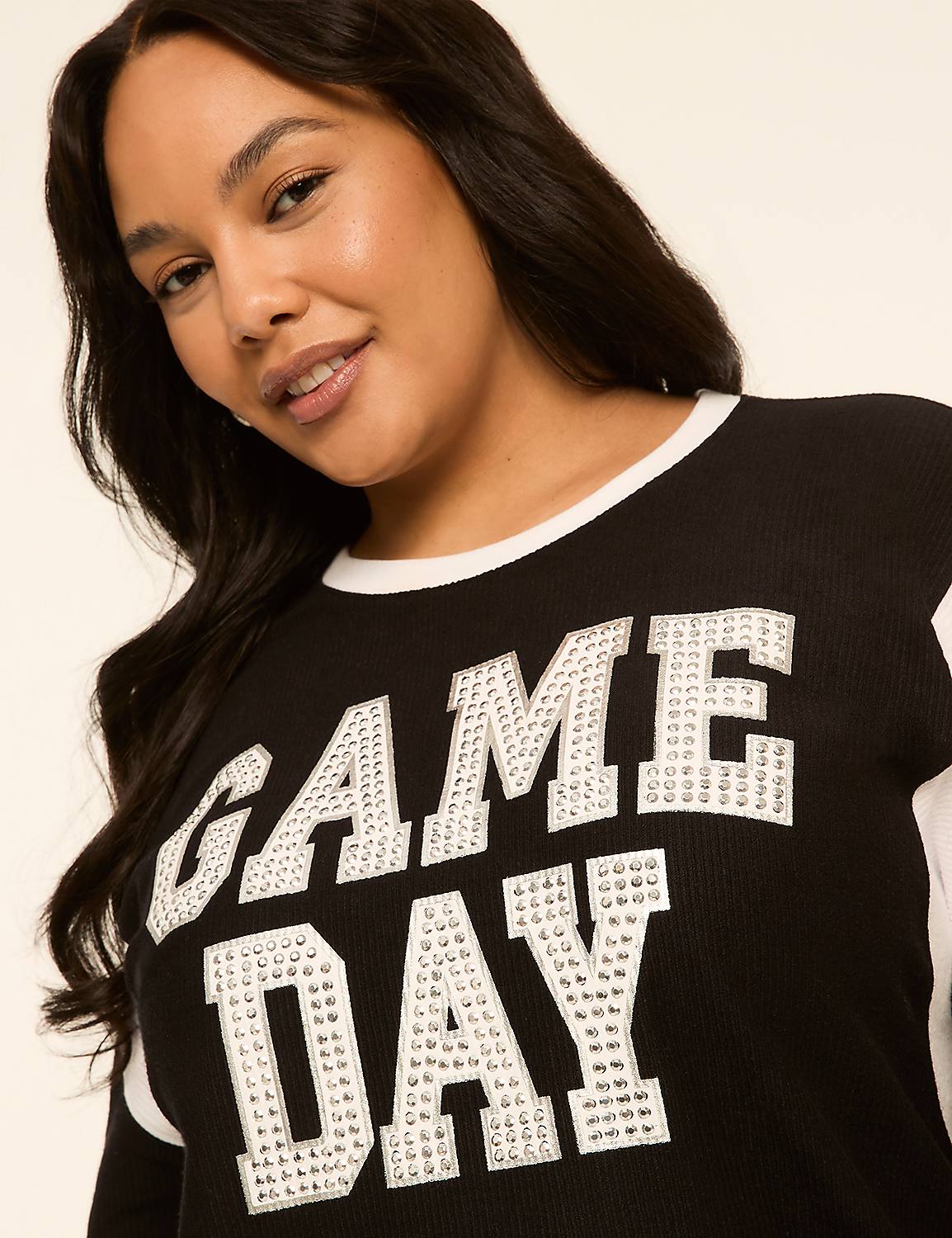 A woman with long dark hair smiles as she wears a black "GAME DAY" sweatshirt with white trim against a plain, light background. Product Image 4