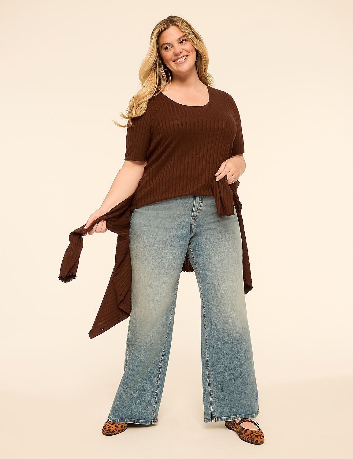 A smiling woman in a brown tunic and light-wash jeans stands against a plain, light-colored background. Product Image 3