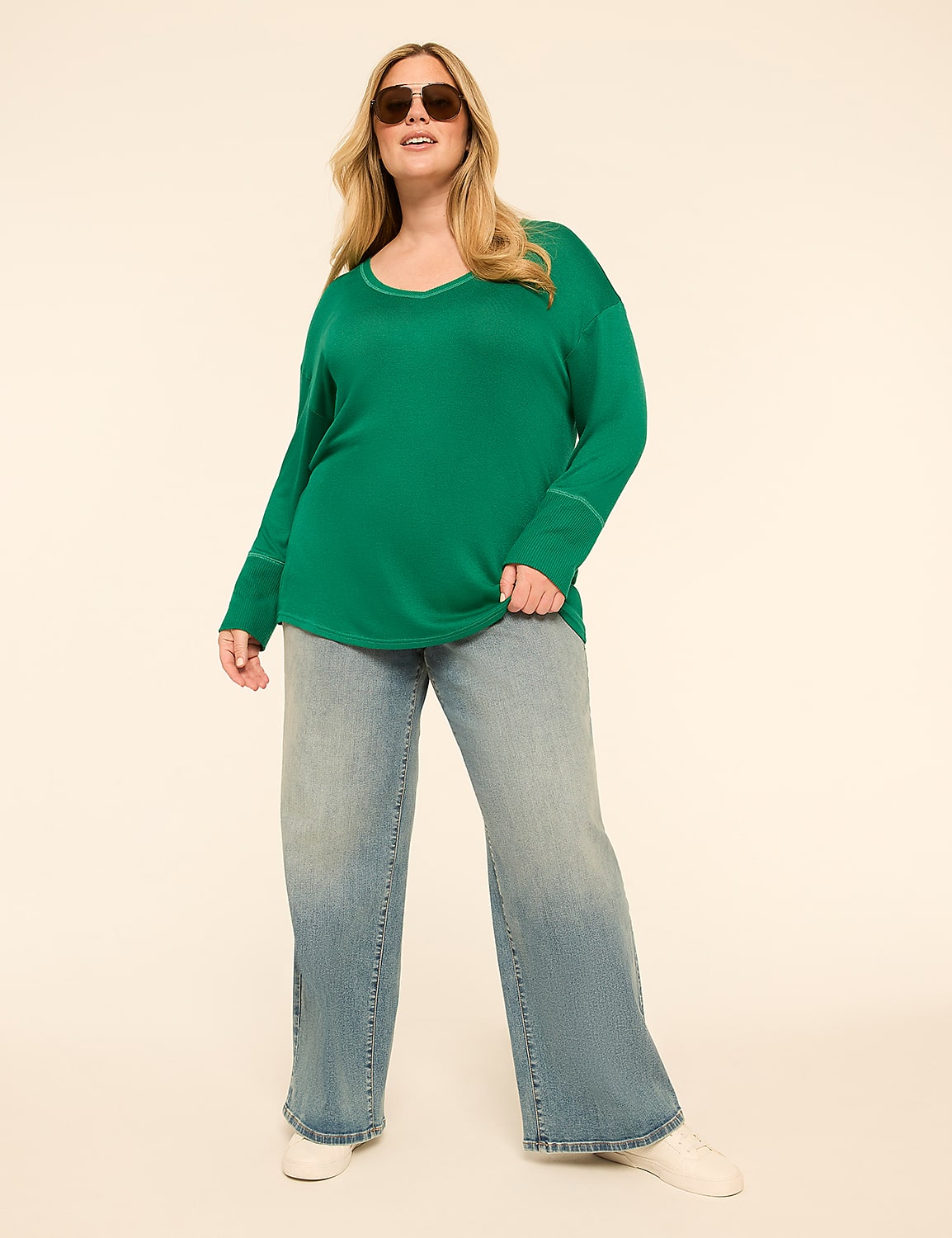 A woman in a green sweater and wide-leg jeans stands against a plain, light-colored background. Product Image 3