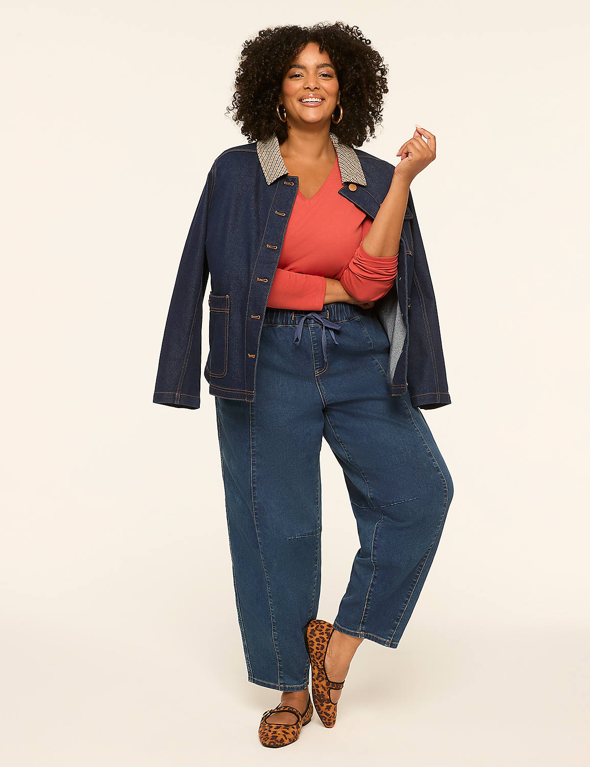 A smiling woman in a denim jacket and coral top stands against a plain, light-colored background. Product Image 3