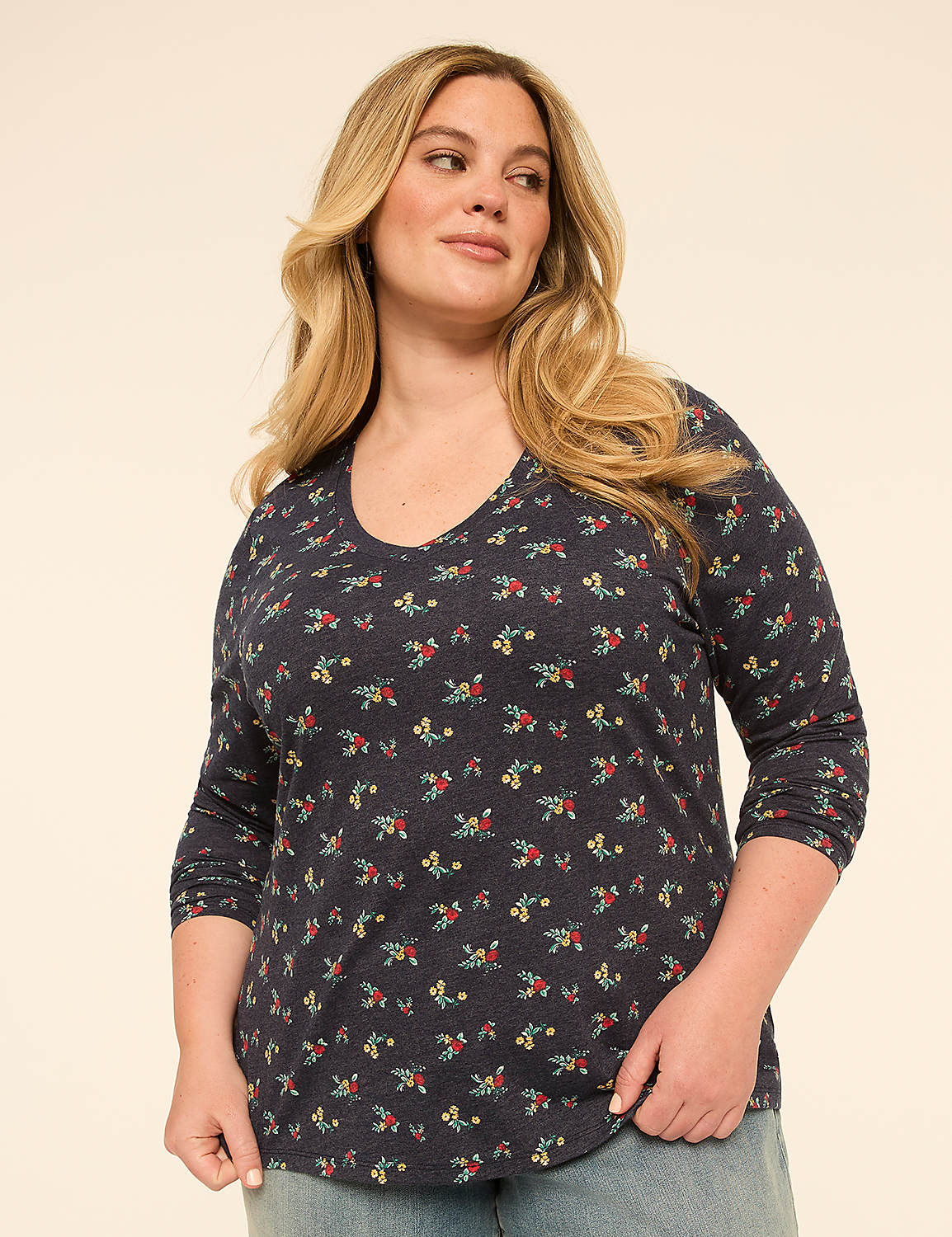 A woman with blonde hair and a floral shirt stands against a plain, light-colored background. Product Image 1