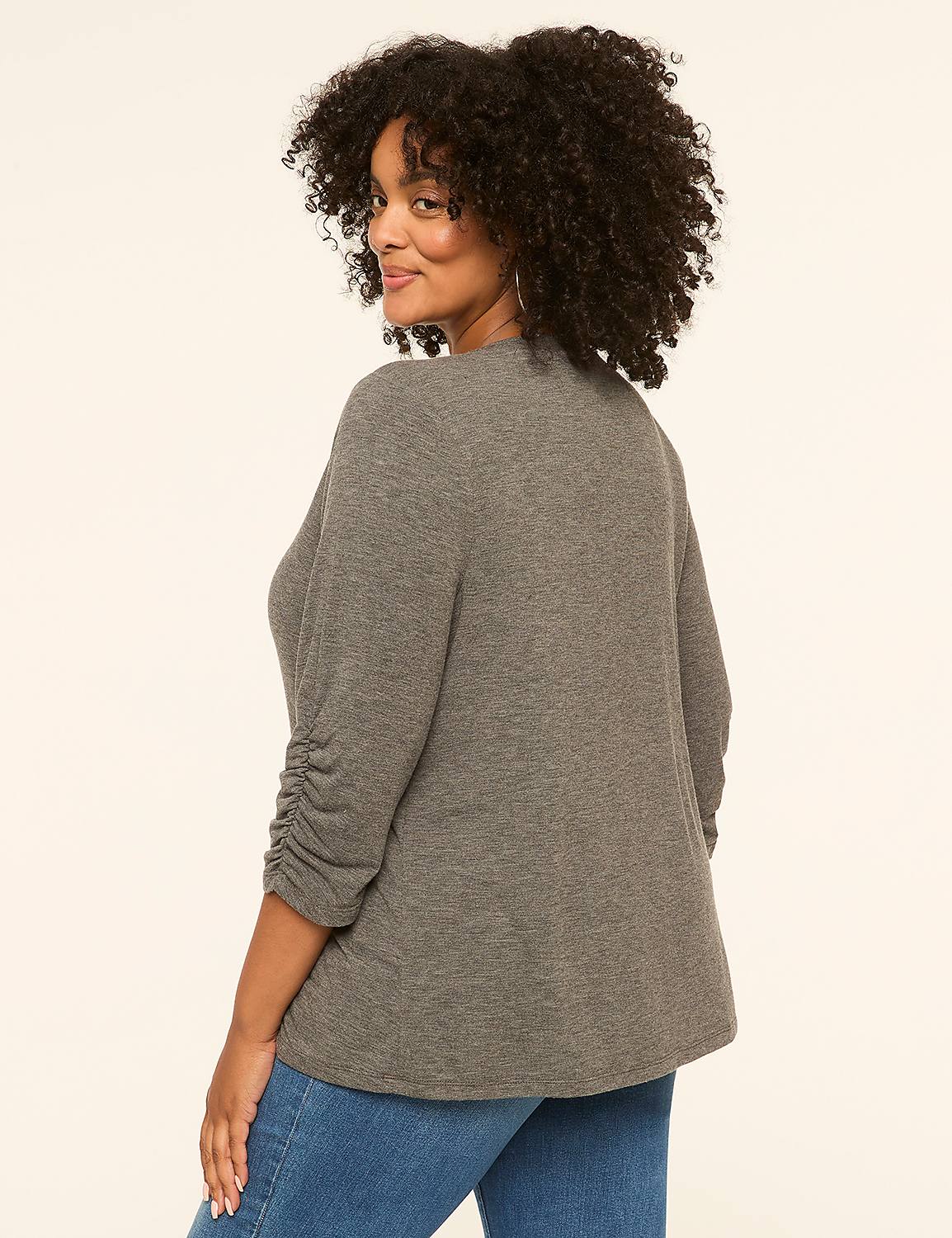 A woman in a grey cardigan and blue jeans stands against a plain cream background. Product Image 2