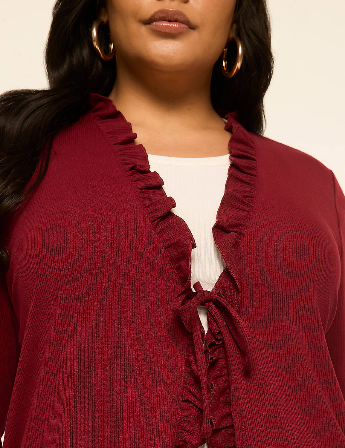 A woman in a maroon ruffled cardigan tied with a bow over a white top stands against a plain beige background. Product Image 4