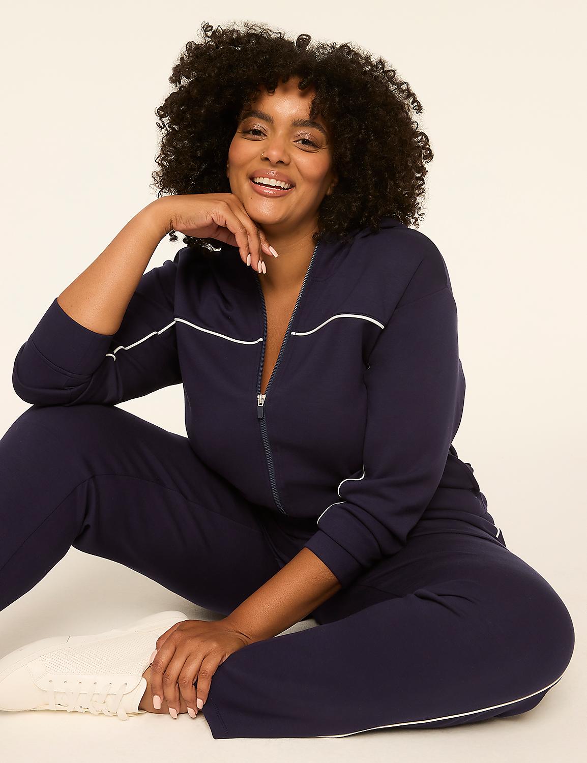 A smiling woman in a navy blue tracksuit with white piping sits on a plain, light-colored background. Product Image 3
