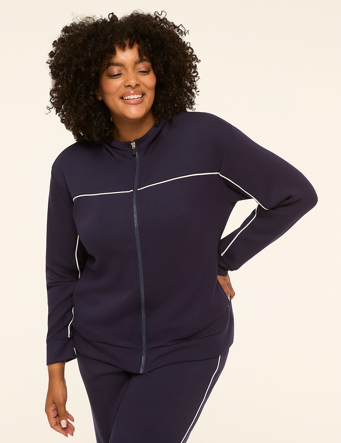 A smiling woman in a navy blue tracksuit with white piping stands against a plain, light-colored background. Product Image 1