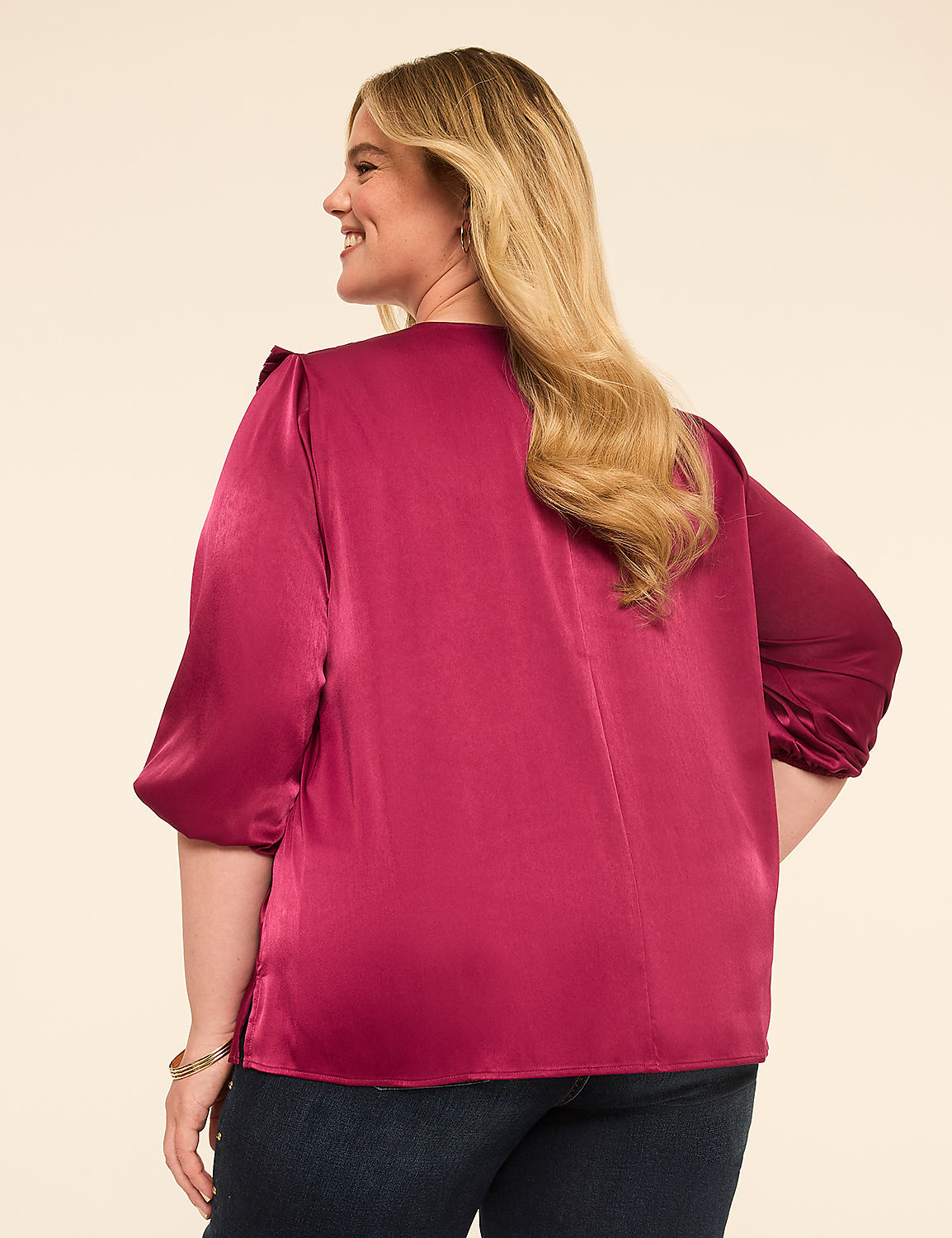 A woman in a satin magenta blouse and dark jeans stands against a plain cream background. Product Image 2
