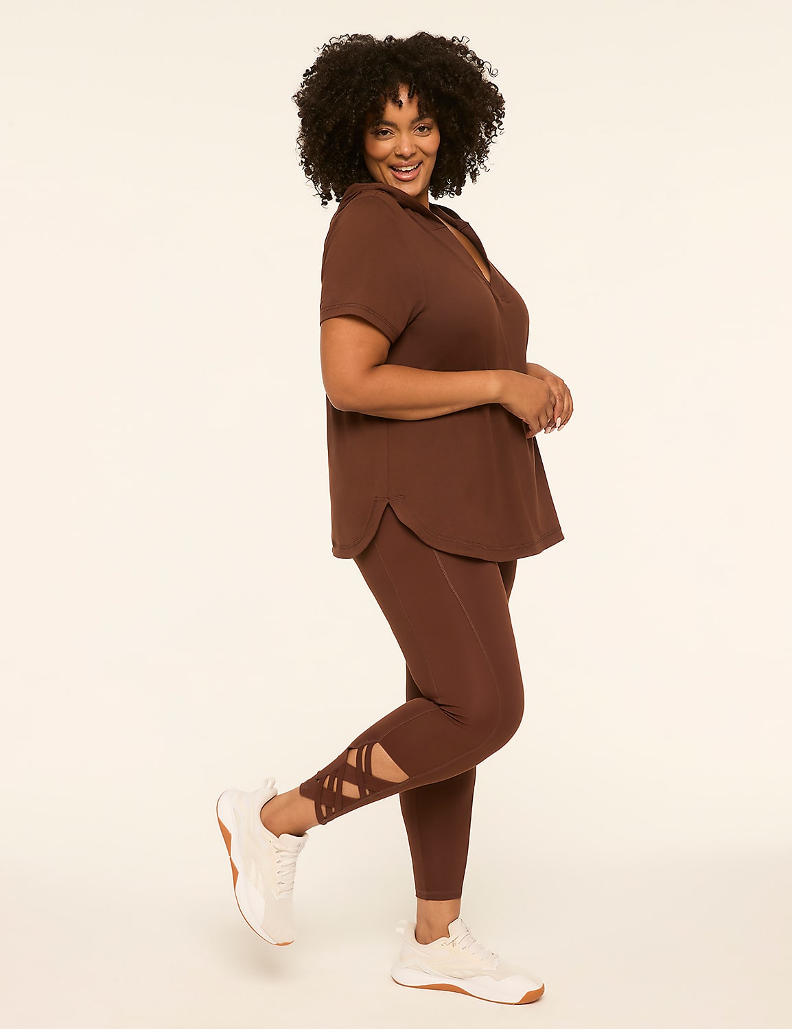 A woman in a brown top and leggings with criss-cross detailing on the ankles poses against a plain, light-colored background. Product Image 3