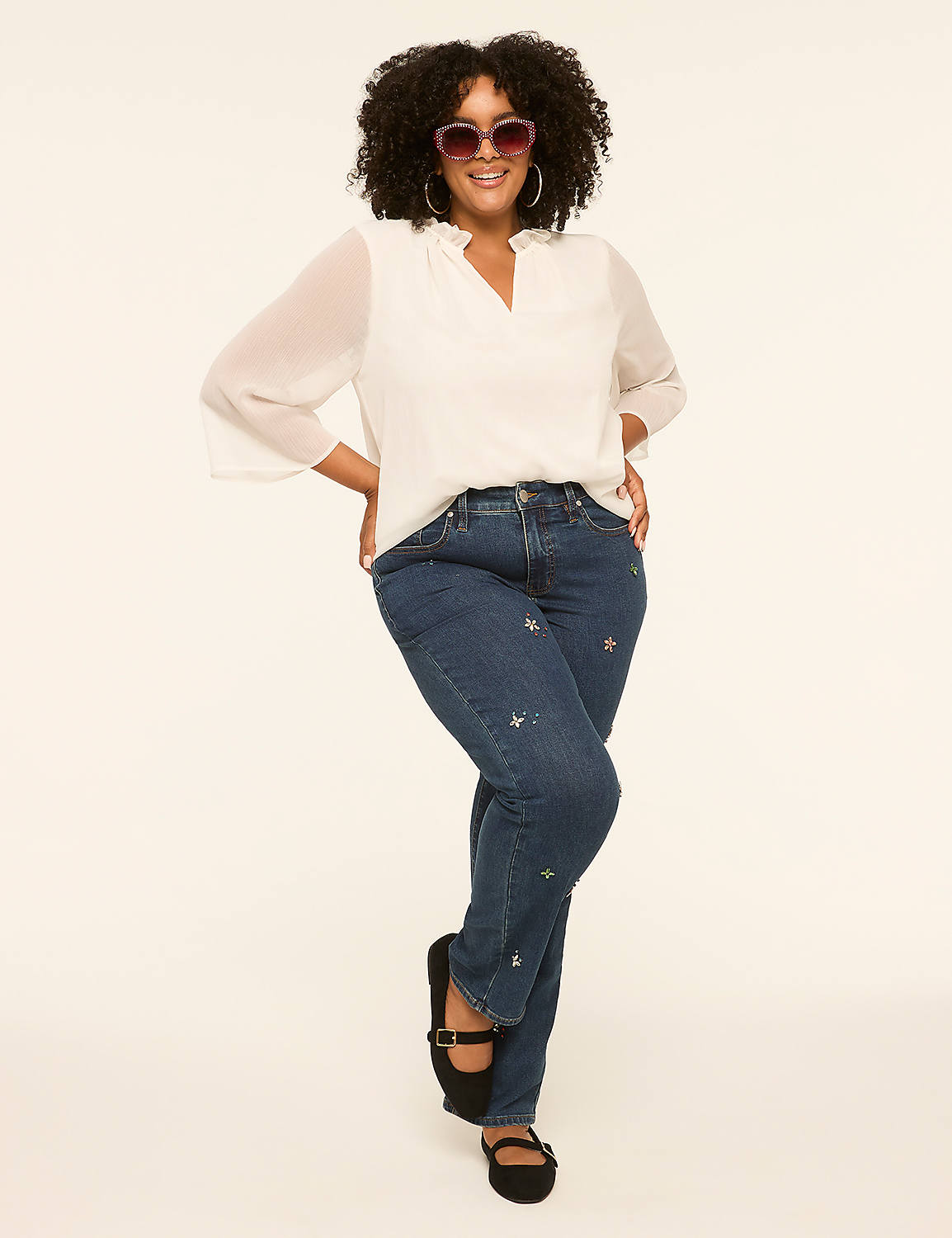 A smiling woman with curly hair and heart-shaped sunglasses poses in front of a plain, light-colored background. Product Image 3