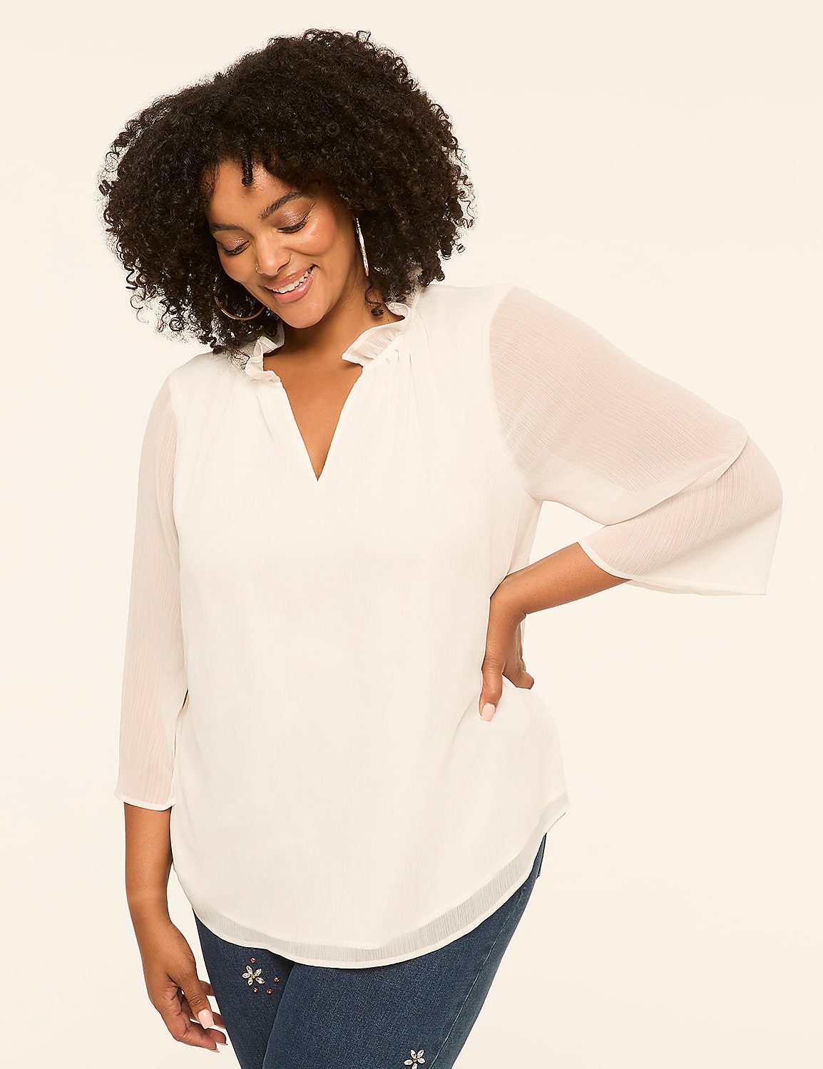 A smiling woman in a white blouse stands against a plain, light-colored background. Product Image 1