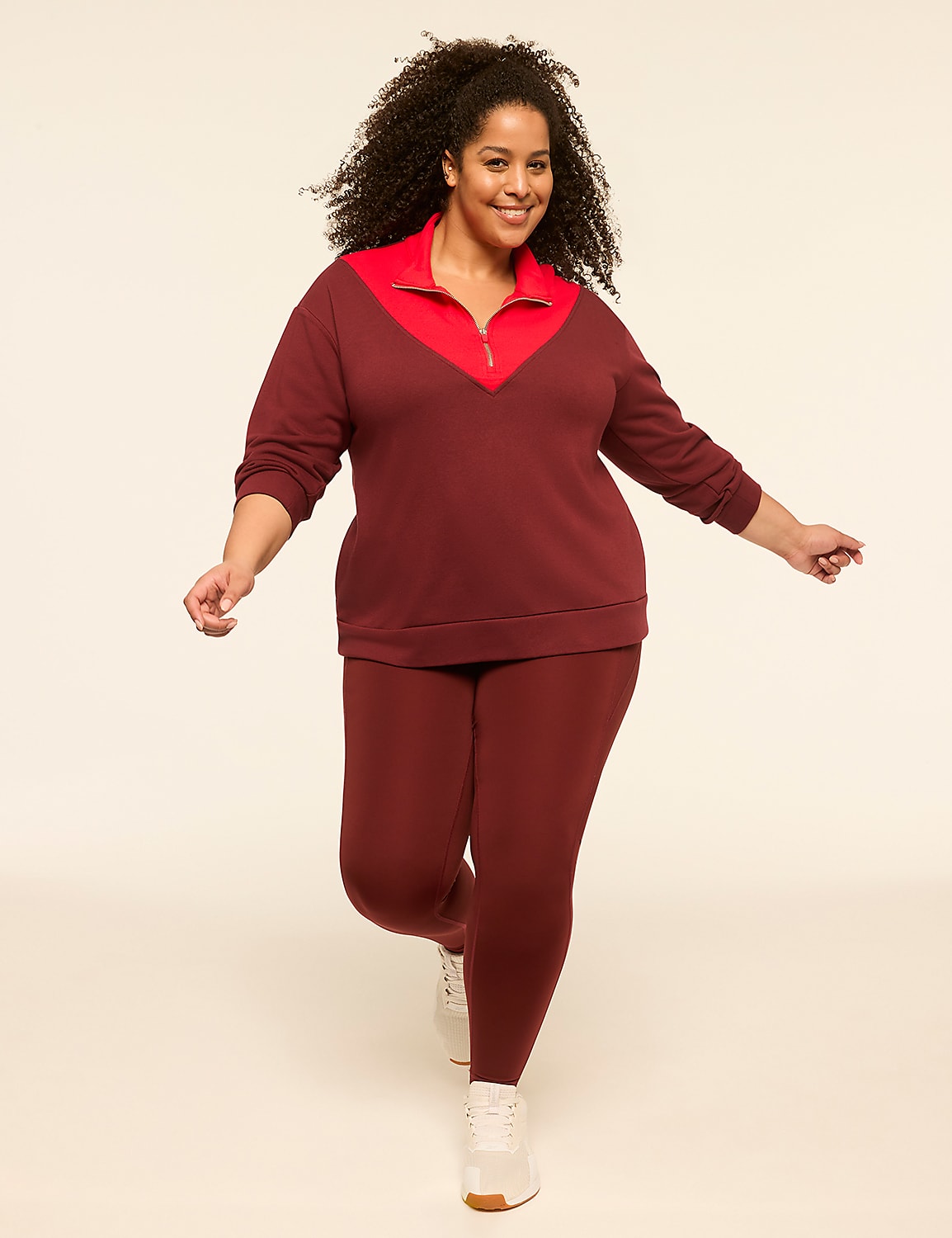 A smiling woman in a maroon and red athletic set poses against a plain, light-colored background. Product Image 3