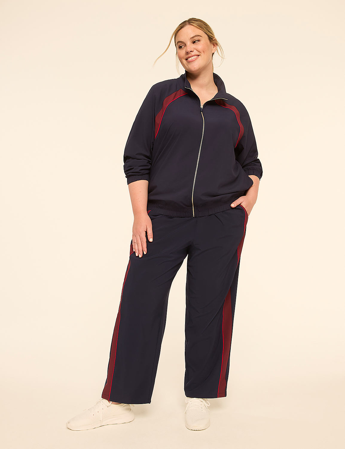 A smiling woman in a navy tracksuit with maroon accents stands against a plain, light-colored background. Product Image 3