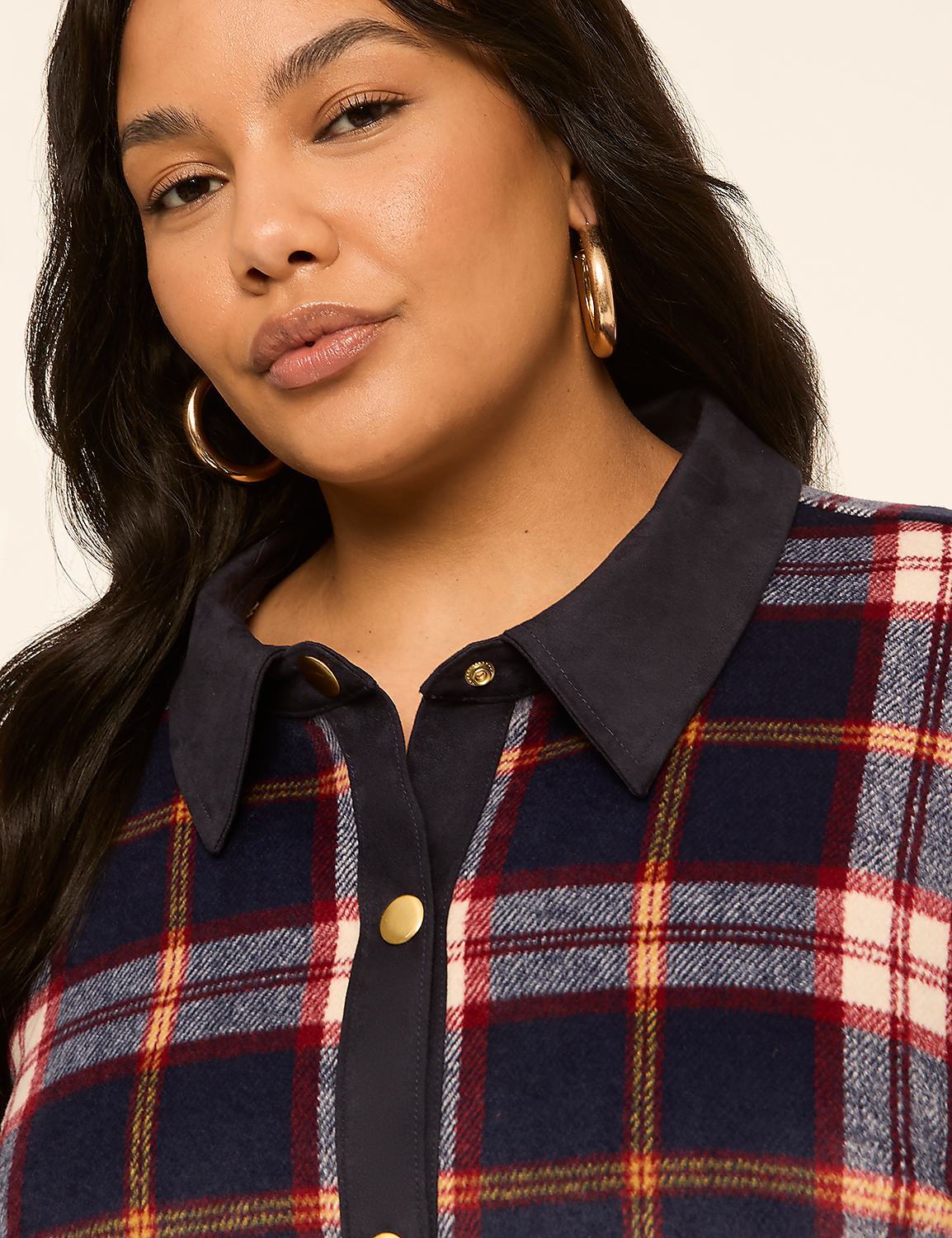 A woman with hoop earrings smiles softly in the foreground, wearing a navy, red, and cream plaid shirt with a dark collar, against a plain, light background. Product Image 4
