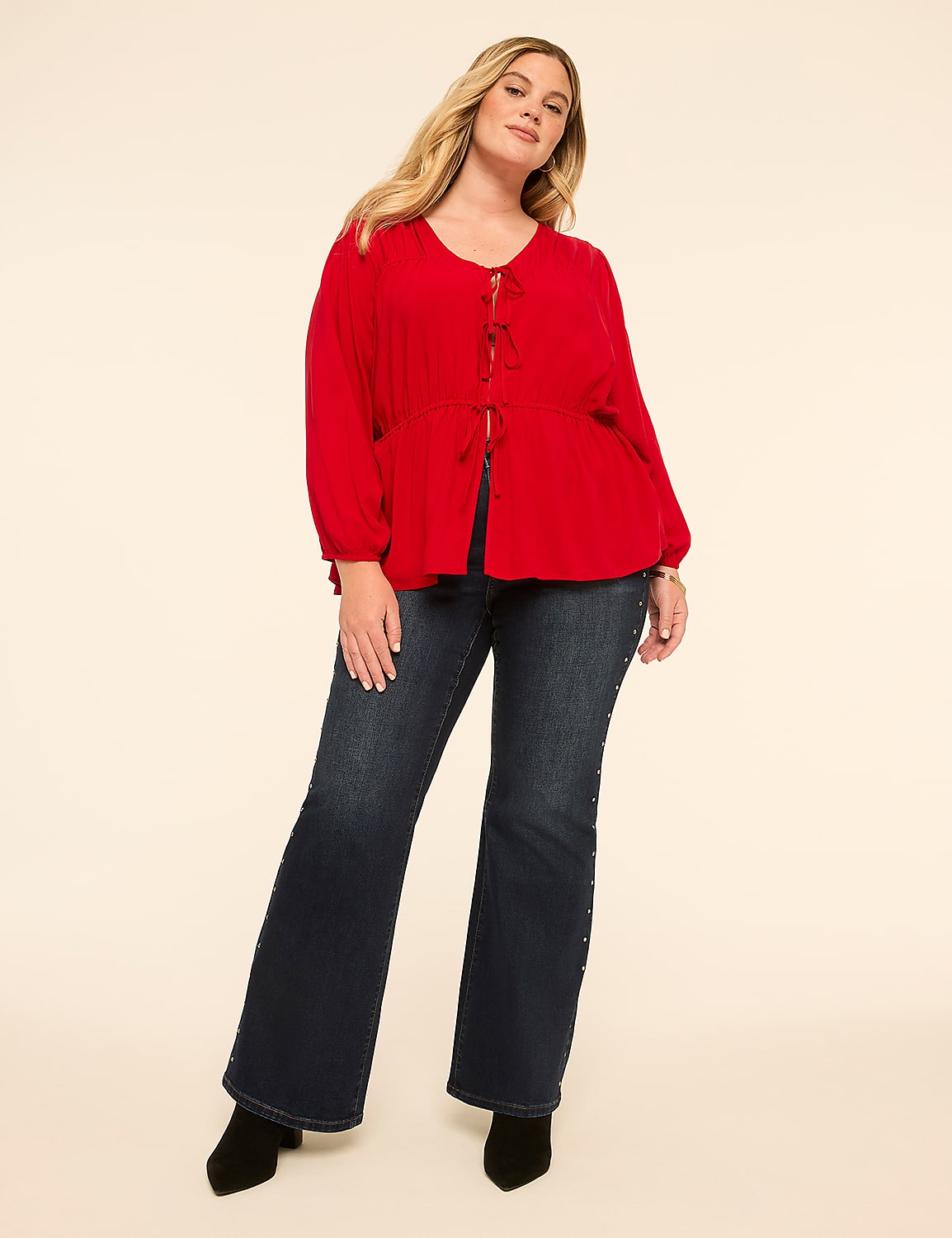 A woman in a red top and dark jeans stands against a plain cream background. Product Image 3
