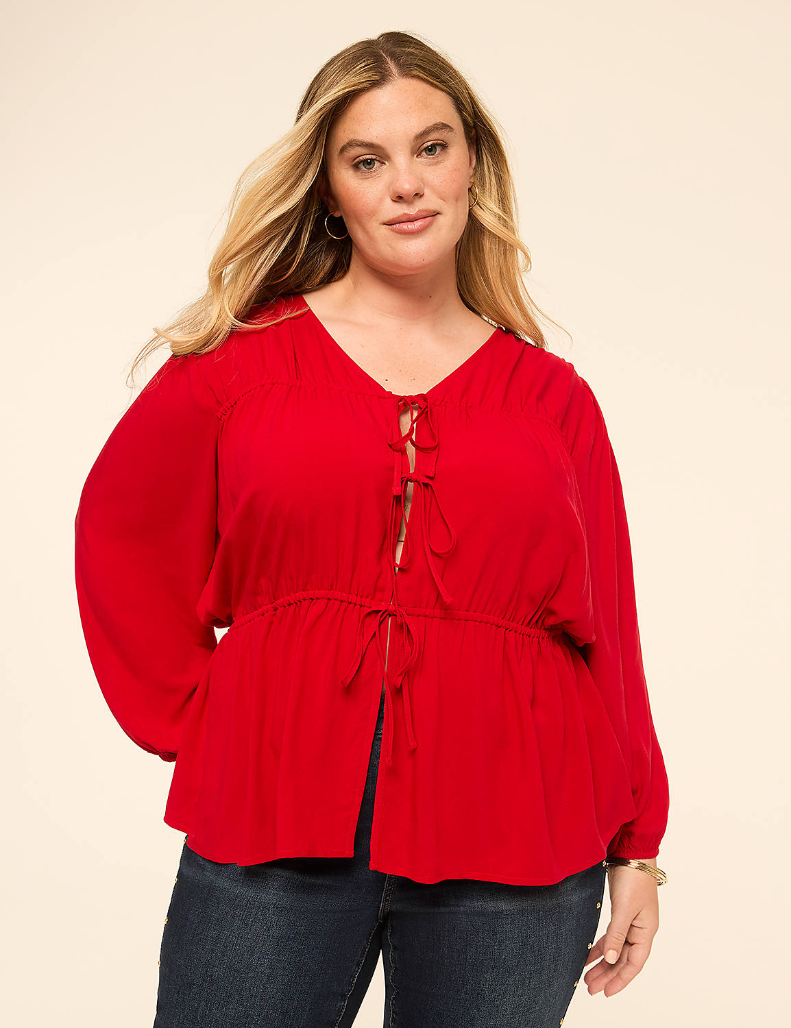 A woman in a red blouse and jeans stands against a plain, light-colored background. Product Image 1