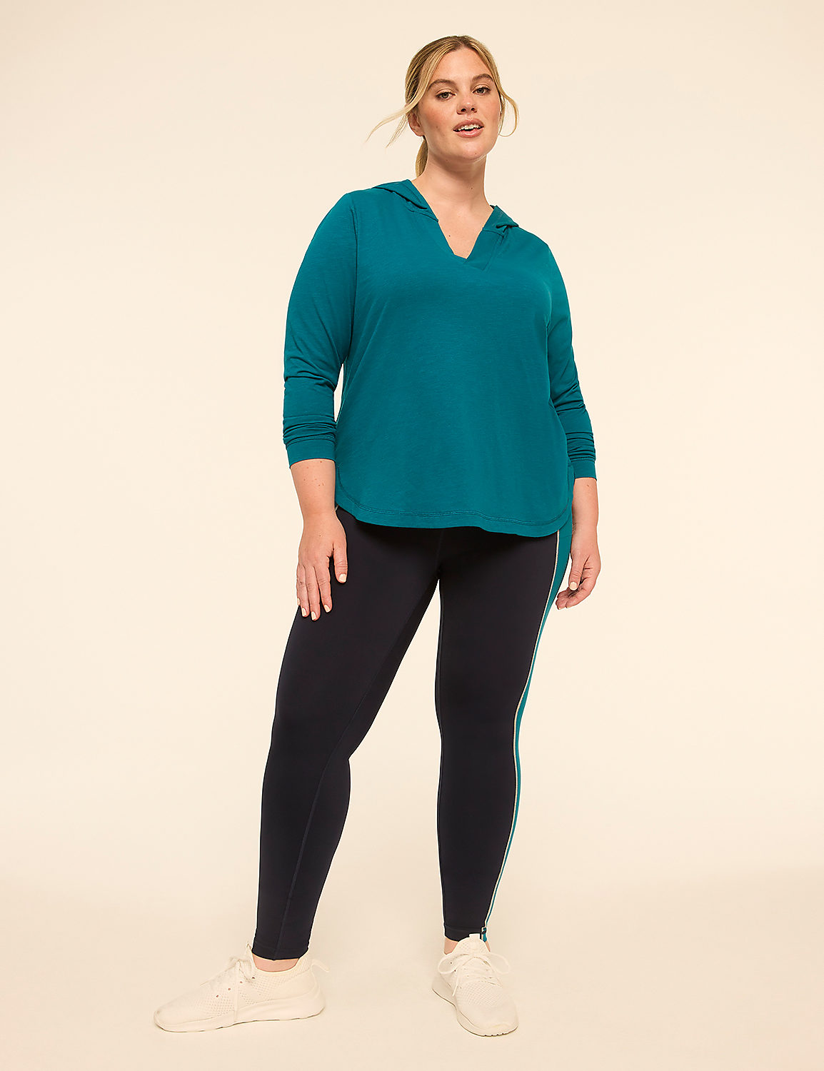 A woman in a teal hoodie and navy leggings stands against a plain, light-colored background. Product Image 3