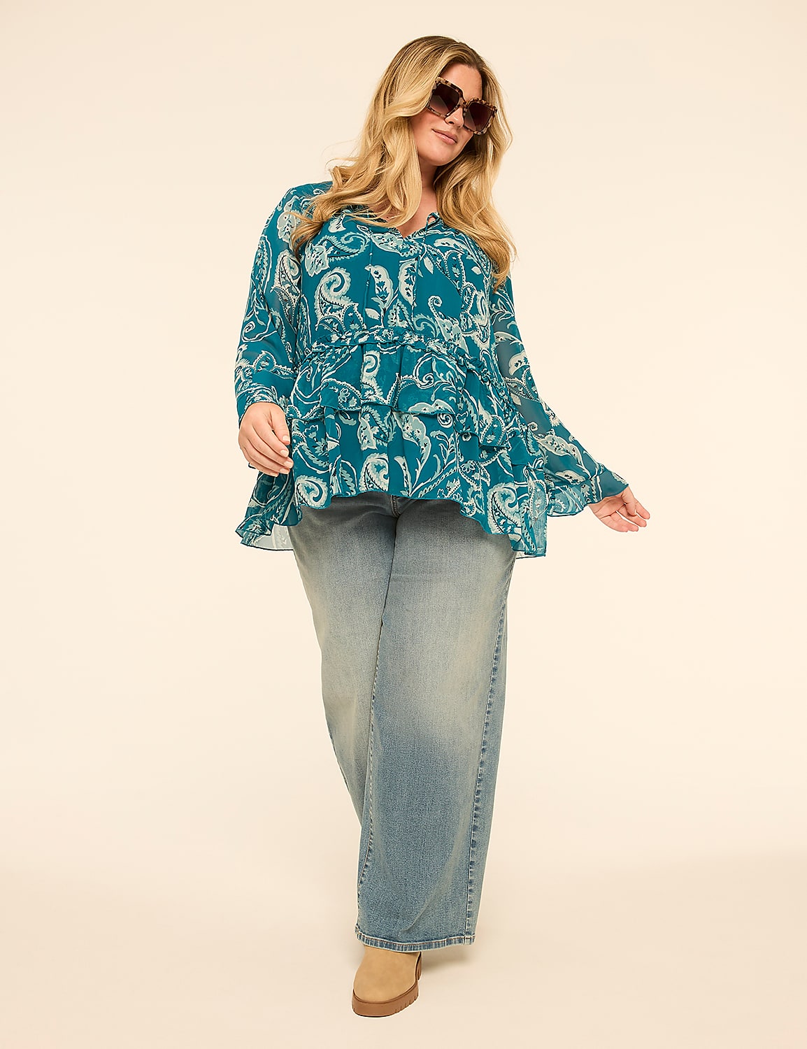 A woman in a teal paisley-print blouse and wide-leg jeans stands against a plain, light-colored background. Product Image 3