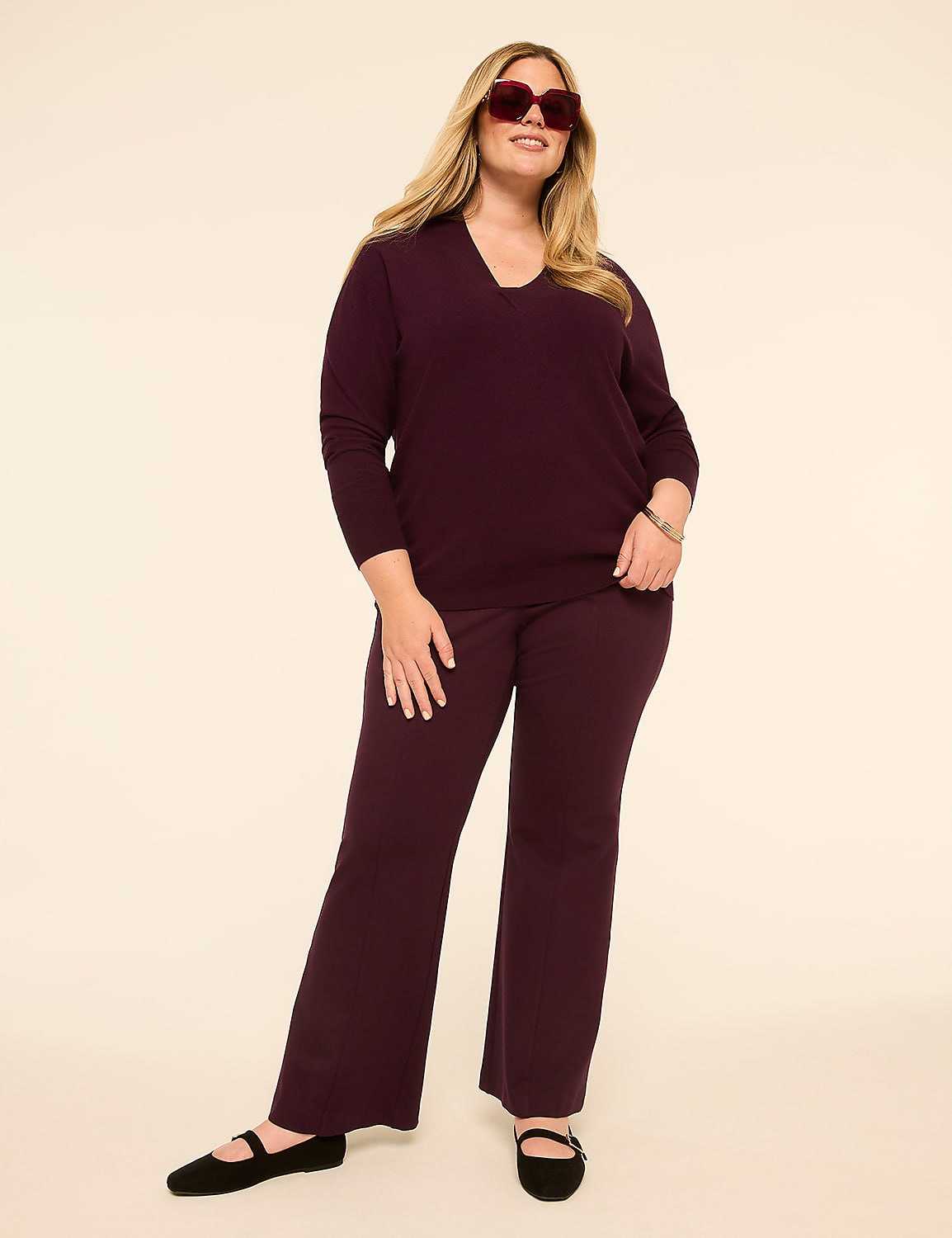 A plus-size woman in a plum v-neck sweater and matching pants stands against a plain, light-colored background. Product Image 3