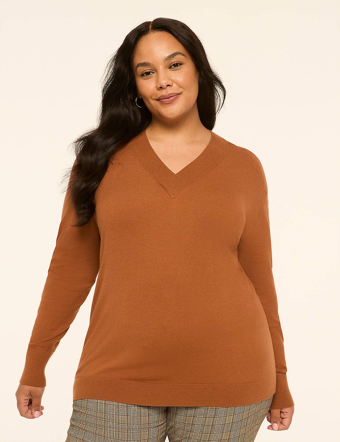 A woman in a brown v-neck sweater and plaid pants stands against a plain, light-colored background. Product Image 1