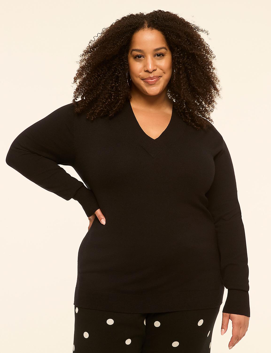 A woman with curly hair and a black v-neck sweater stands against a plain, light-colored background, her lower body adorned with polka-dot pants. Product Image 1