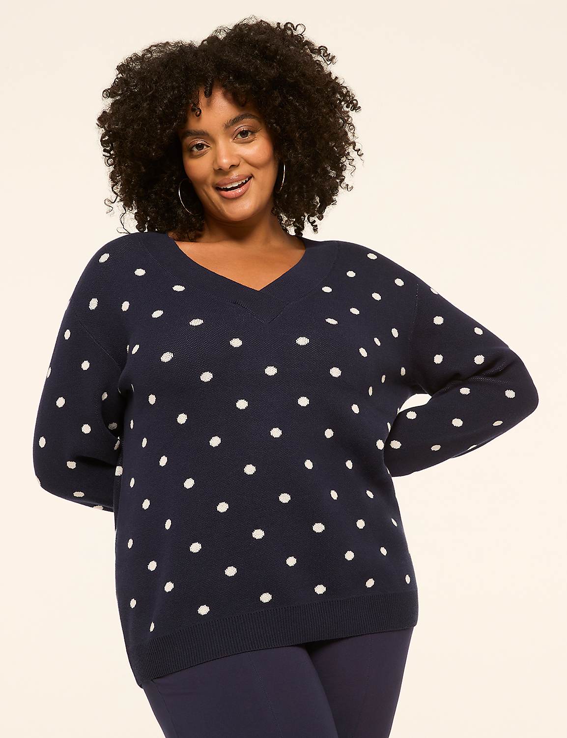A smiling woman in a navy polka dot sweater stands against a plain, light-colored background. Product Image 1