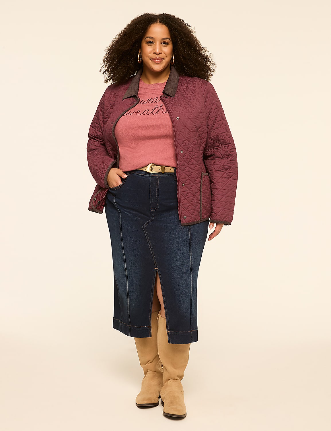 A woman with curly hair stands in a quilted maroon jacket, pink sweatshirt, and denim skirt with tan boots against a plain cream background. Product Image 3