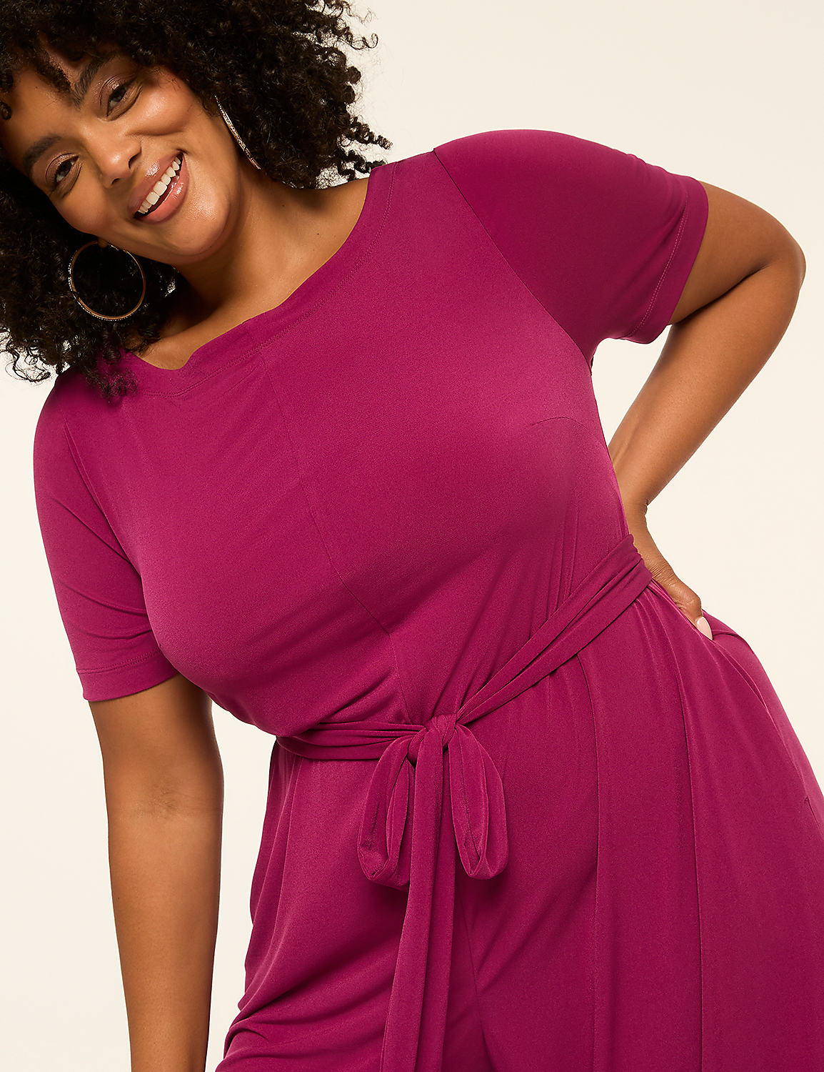 A smiling woman in a magenta jumpsuit with a tie waist is posed against a plain, light background. Product Image 3