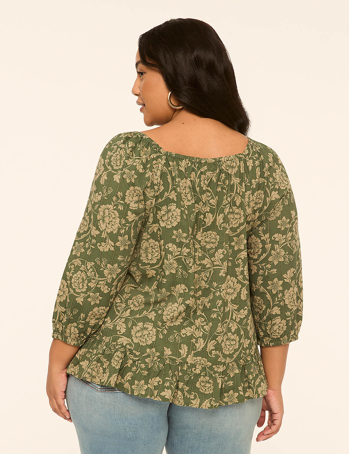 A woman in a floral green top and blue jeans stands against a plain, light-colored background. Product Image 2