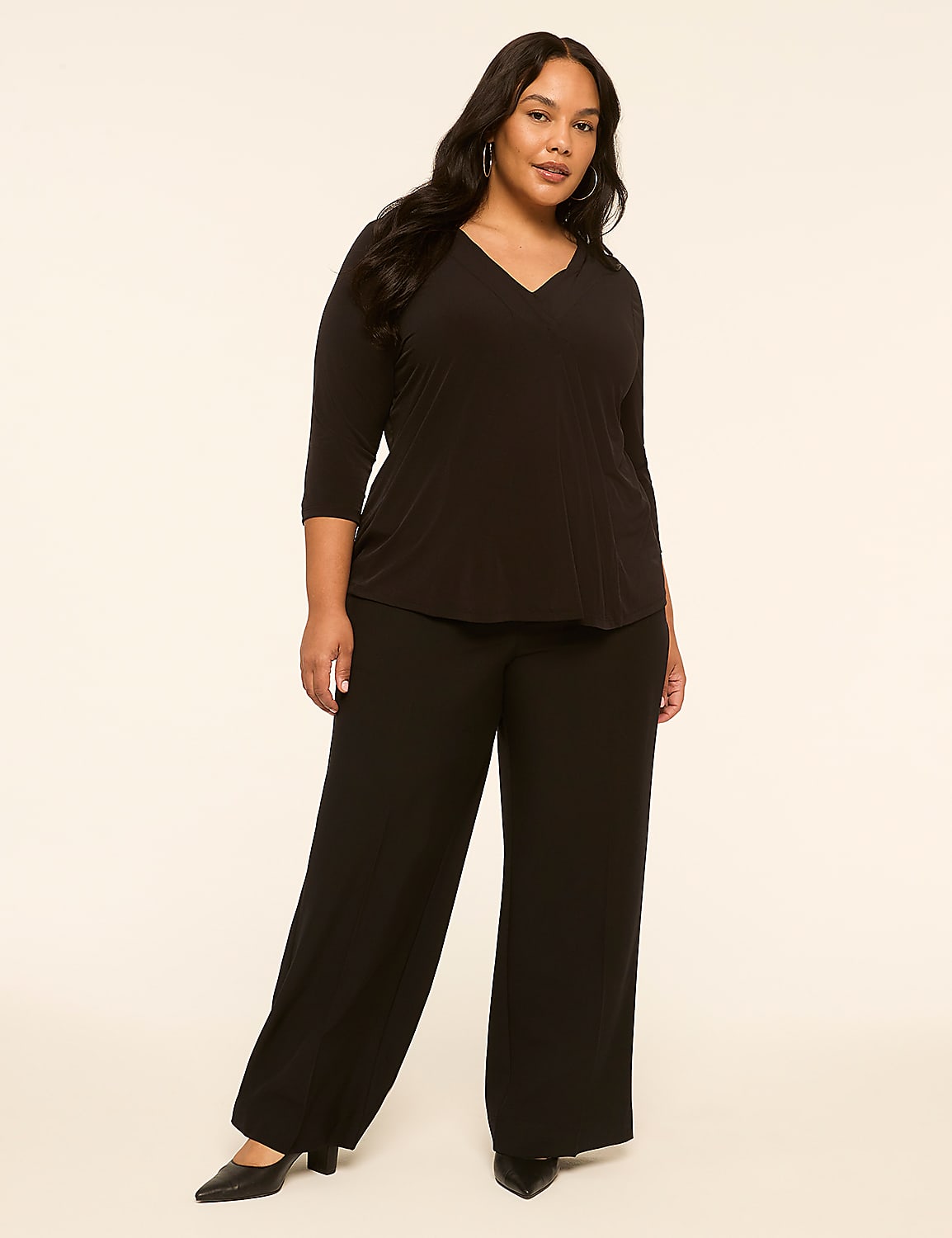 A woman in a black v-neck top and wide-leg pants stands against a plain, light-colored background. Product Image 3
