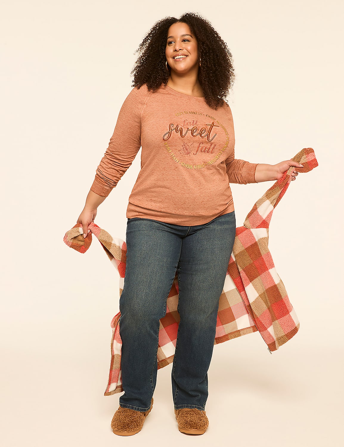 A smiling woman in a long-sleeved shirt and jeans holds a plaid blanket against a plain background. Product Image 3