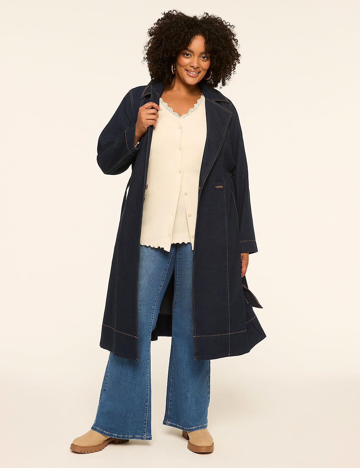 A woman in a long navy coat and flared jeans stands against a plain, light-colored background. Product Image 3